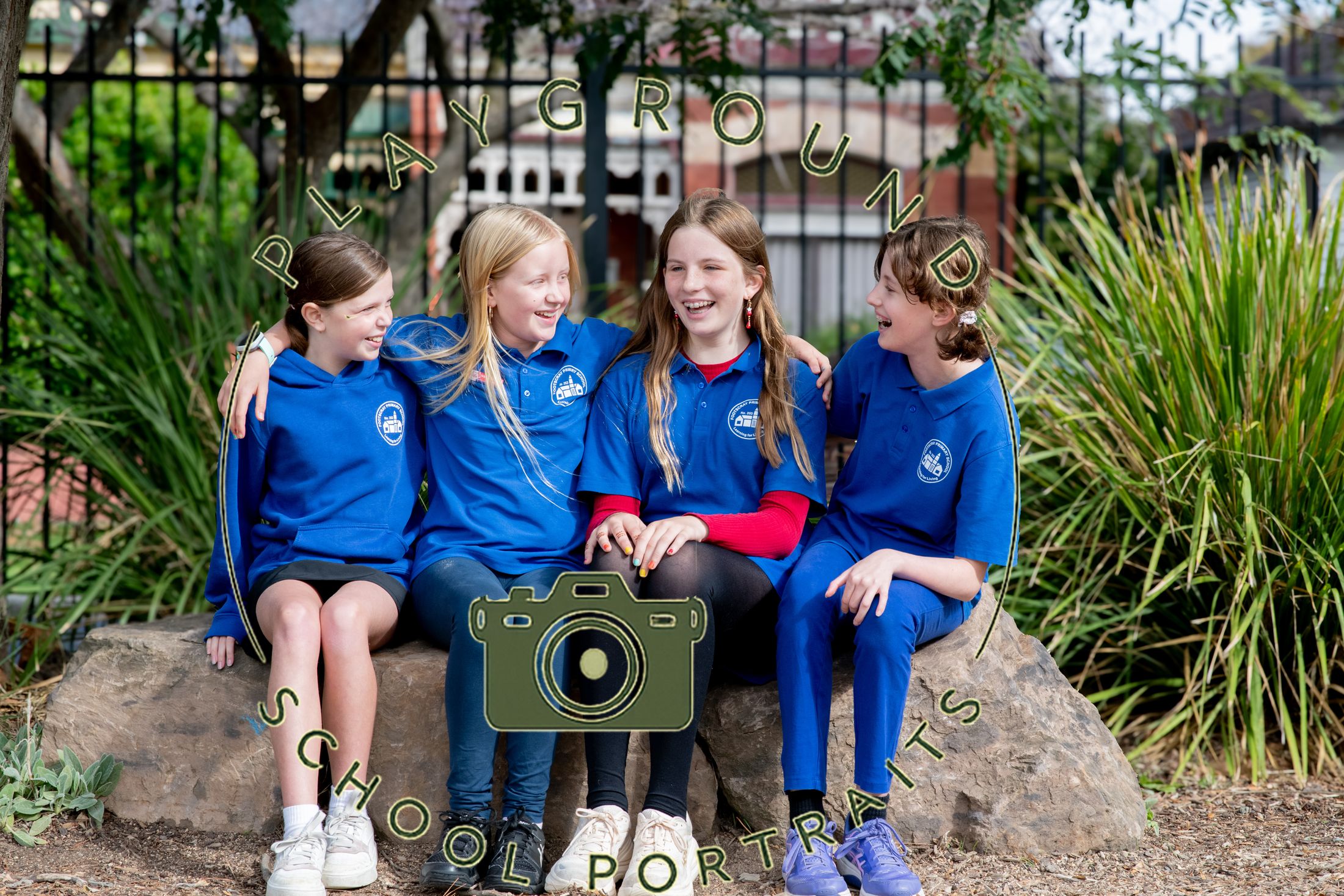 Two students in school uniforms sitting back to back, smiling in a garden